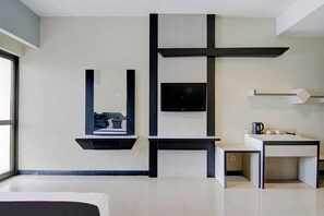 A modern hotel room with a flat-screen TV, a built-in desk, and a large window. - Townhouse Oak Pekanbaru Near Mall Pekanbaru (Pekanbaru)