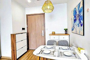 A dining area with a table set for four, a wooden cabinet, a door, and a wall-mounted painting.