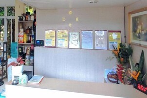 Un mostrador de recepción con un mostrador, un teléfono en la pared y varios avisos enmarcados.