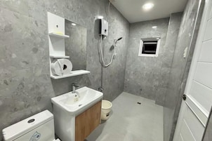 Un baño moderno con inodoro, lavamanos y ducha.