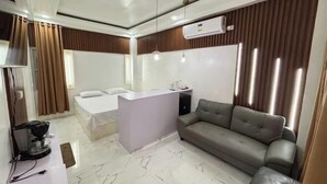 Una habitación de hotel moderna con cama, sofá, escritorio pequeño y televisor.
