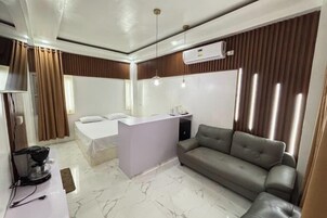 Una habitación de hotel moderna con cama, sofá, escritorio pequeño y televisor.