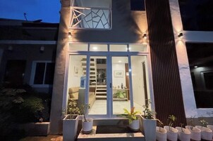 Un edificio moderno con entrada de vidrio, una escalera que conduce al piso superior y plantas en macetas afuera.