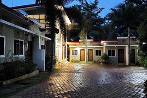A residential property with a paved driveway, a covered outdoor area, and a building with multiple doors and windows. - Alejandro's Suites & Venue (Valencia)