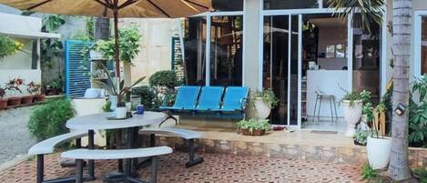 An outdoor patio with a table and chairs, a blue sofa, and a large umbrella.