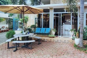 An outdoor patio with a table and chairs, a blue sofa, and a large umbrella. - Alejandro's Suites & Venue (Valencia)