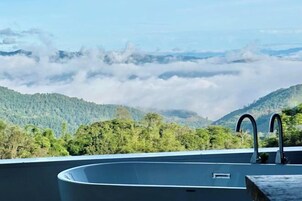 Piscina en la azotea con vistas a montañas boscosas y nubes.