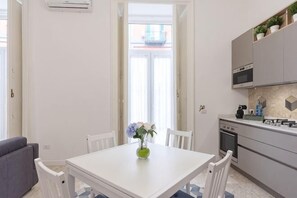 A modern kitchen with white cabinets, a dining table with chairs, and a vase with flowers. - L'Orchidea al Museo appartament in the center (Naples)