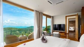 A hotel room with a large bed, a television, and a view of the landscape. - Villa Bella Vista Samui - 360 Degrees Mountain View (Koh Samui)