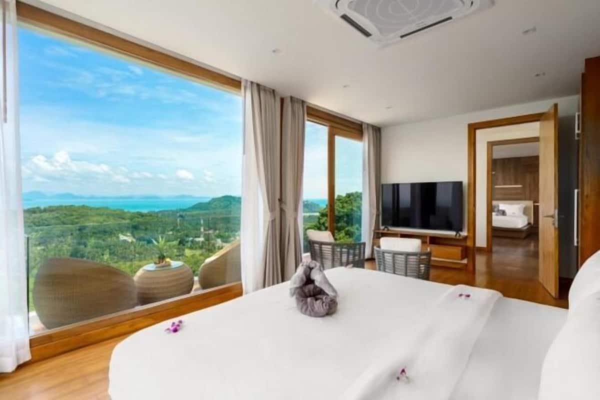 A hotel room with a large bed, a television, and a view of the landscape.