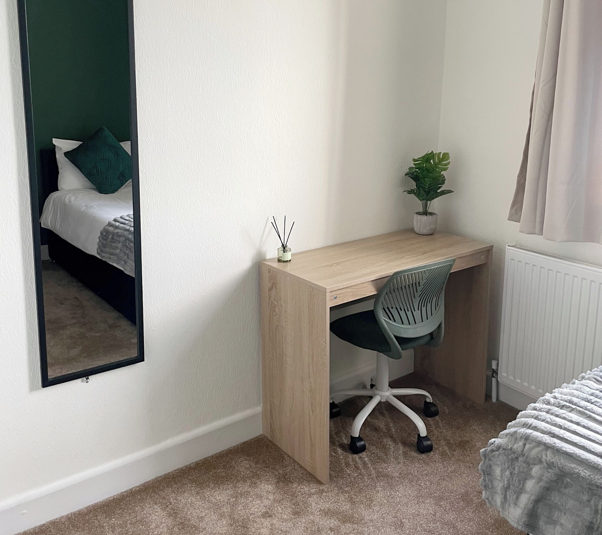 A compact bedroom with a bed, a desk, and a chair.