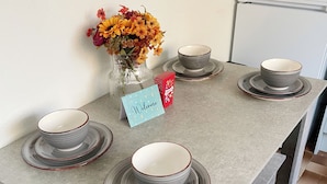 A kitchen counter with four stacked bowls, a vase with flowers, and a 'Welcome' card. - Your Home-from-home - Business & Families - 6 Beds (Ilford)