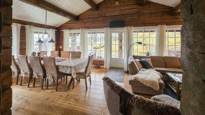 A rustic interior with a wooden dining table, wicker chairs, a sofa, and large windows offering a view of the outdoors. - Cozy home in Rauland with WiFi (Rauland)