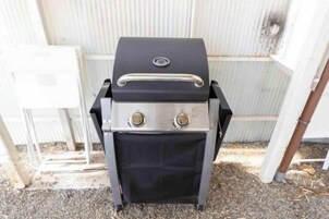 Una parrilla portátil con panel de control y tapa, ubicada al aire libre.