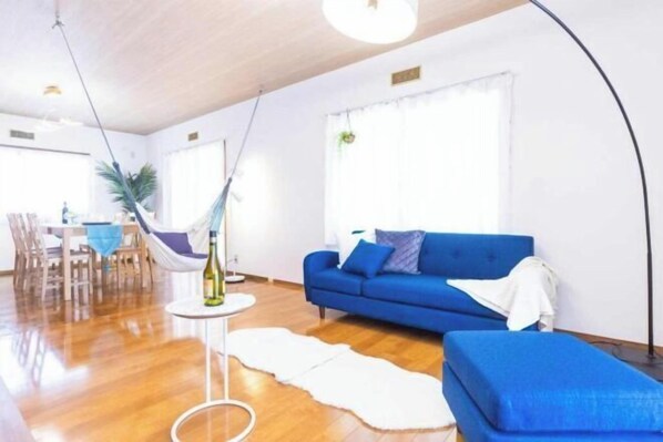 Una sala de estar con un sofá azul, un tapete blanco y un sillón colgante.