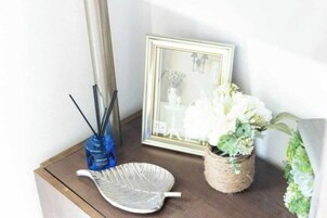 Un cuadro enmarco, un jarrón azul con una planta y una hoja decorativa blanca sobre una superficie de madera.