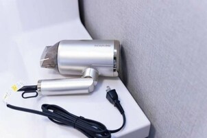 Un purificador de aire portátil con cable de alimentación y cable USB sobre una superficie blanca.