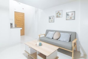 Un salon moderne avec un canapé gris, une table basse en bois et une porte en bois.