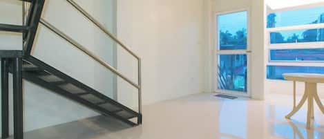 A modern interior with a staircase, a door leading to a balcony, and a table.