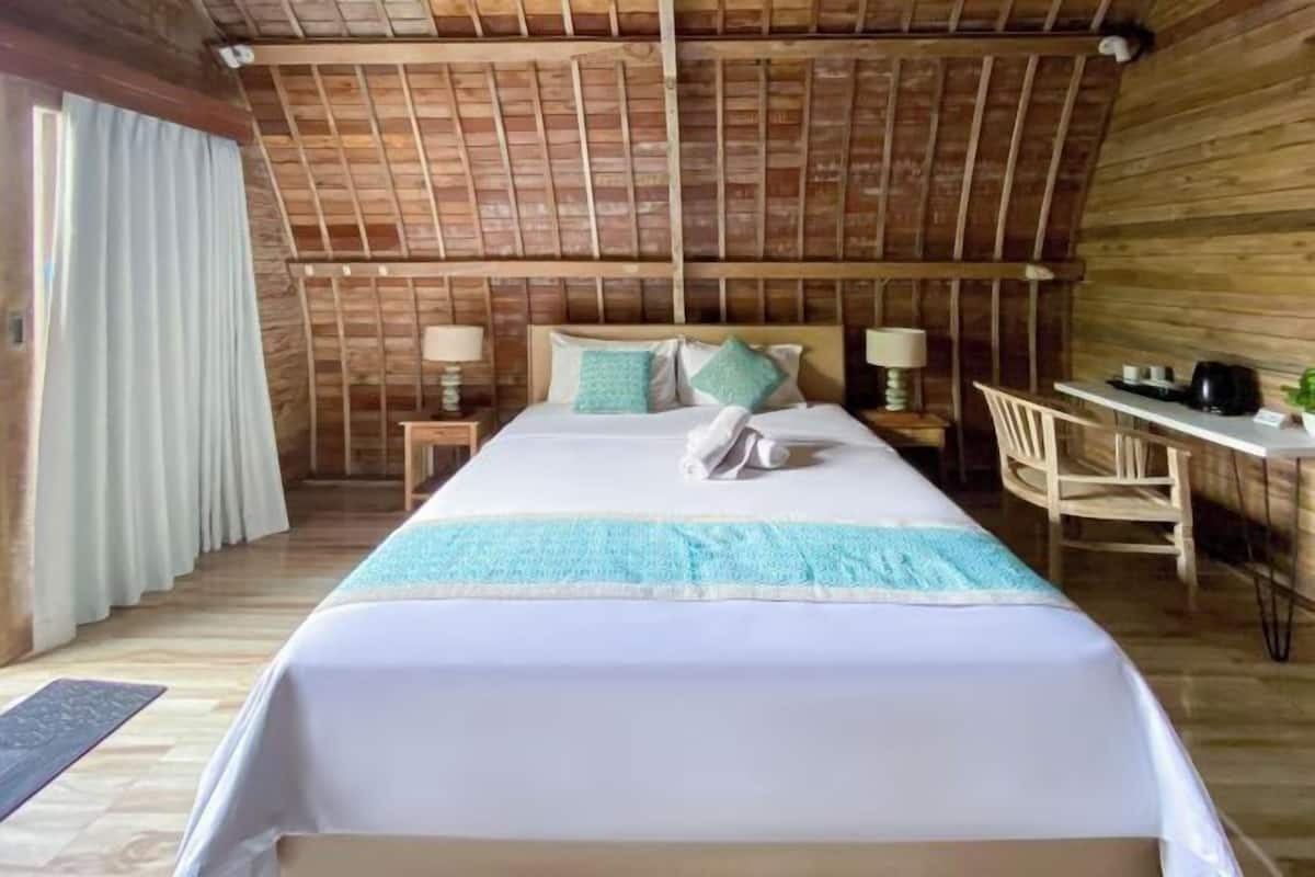 A wooden room with a bed, a desk, and a chair.