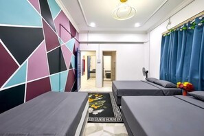 A hotel room with two beds, a geometric-patterned wall, a blue curtain, and a floral rug. - Penang Dream Banglo (Tanjung Bungah)