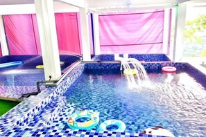 An indoor swimming pool with a tiled floor, a water feature, and inflatable rings. - Penang Dream Banglo (Tanjung Bungah)