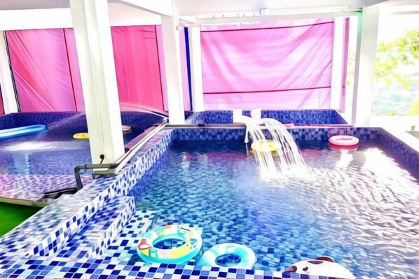 An indoor swimming pool with a tiled floor, a water feature, and inflatable rings. - Penang Dream Banglo (Tanjung Bungah)