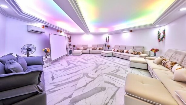 A modern living room with a sectional sofa, a flat-screen TV, and a fan. - Penang Dream Banglo (Tanjung Bungah)