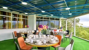 A dining area with round tables, chairs, and a large window with a view of greenery. - Penang Dream Banglo (Tanjung Bungah)