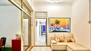A modern living room with a beige sofa, a painting of a sunset, and a red side table. - Penang Dream Banglo (Tanjung Bungah)