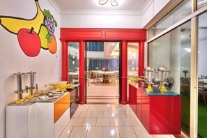A hotel lobby with a red reception desk, a fruit mural, and a view into the dining area. - Penang Dream Banglo (Tanjung Bungah)