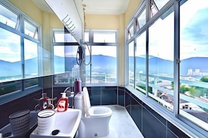 Uma casa de banho moderna com sanita, lavatório e amplas janelas com vista para a cidade.