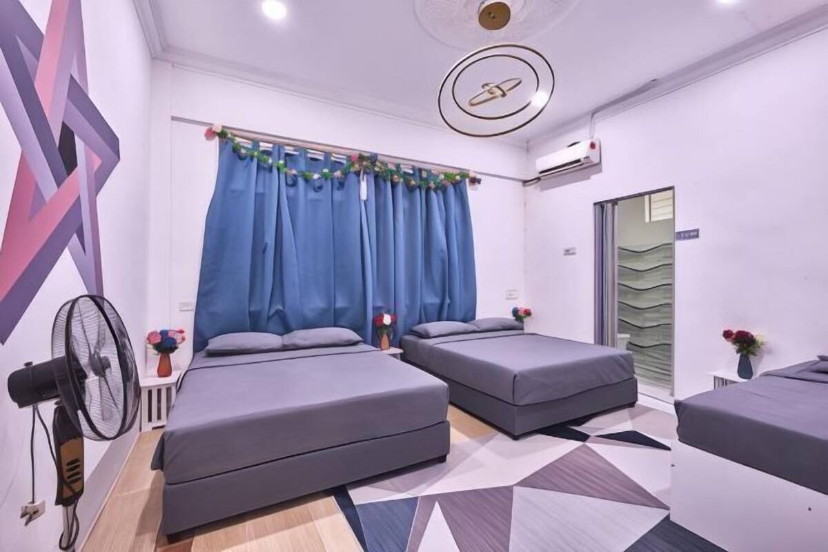 A modern hotel room with two beds, a ceiling fan, and a geometric patterned floor.