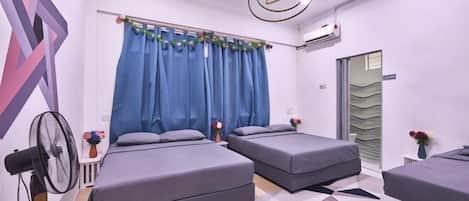 A modern hotel room with two beds, a ceiling fan, and a geometric patterned floor.