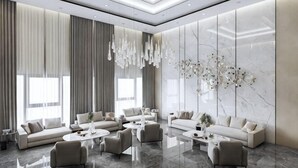 A spacious living room with a high ceiling, large windows, and a modern chandelier. - Wyndham Garden Legend Halong (Ha Long)