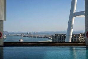 A view from a balcony overlooking a marina with boats and a distant cityscape. - Wyndham Garden Legend Halong (Ha Long)