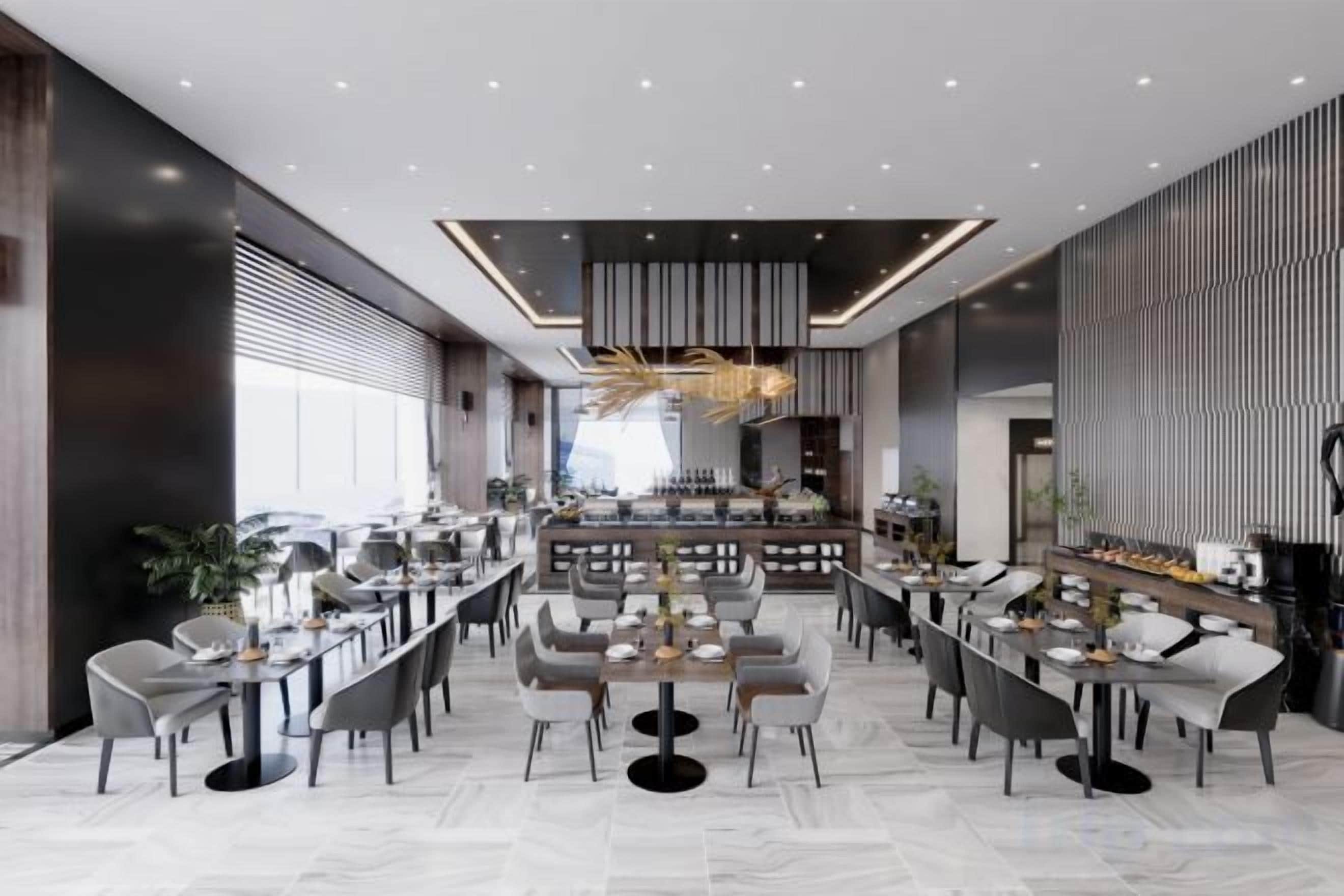 Un restaurant moderne doté d’un bar central, de nombreuses tables et d’un décor intérieur contemporain.