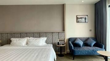 Una habitación de hotel con una cama, un sofá, una mesita y un cuadro colgado en la pared.