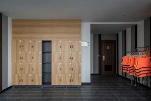A hallway with lockers and a rack of orange life jackets.