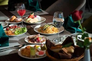 A dining table with various dishes, glasses, and a rose. - Wyndham Garden Legend Halong (Ha Long)