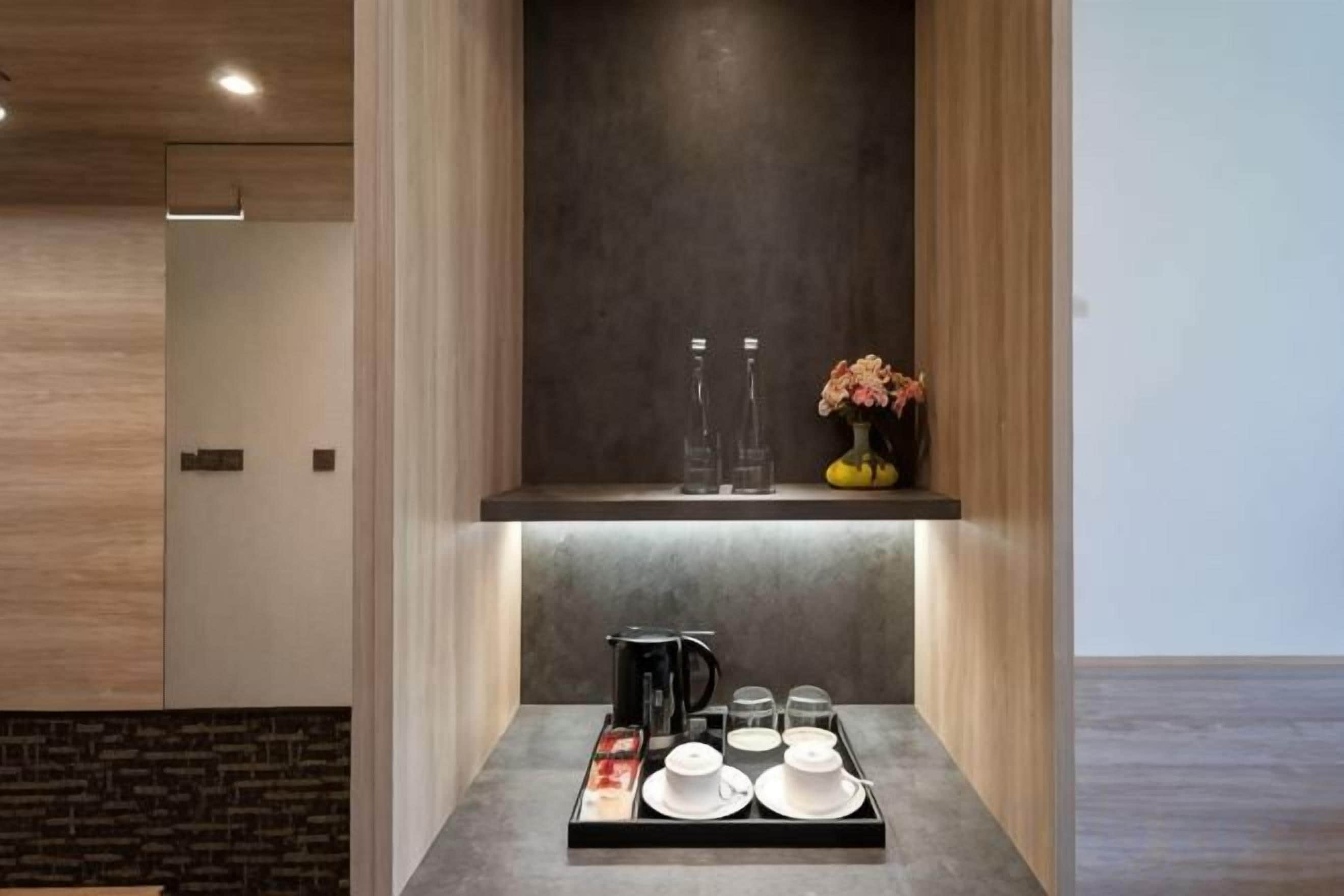 A modern kitchen with a built-in island, a coffee maker, and a vase with flowers.