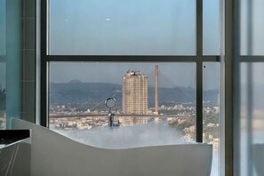 A room with a large window, a view of a cityscape, and a desk with a ring light. - Wyndham Garden Legend Halong (Ha Long)