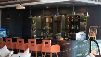 Zona de bar con asientos, una barra y estanterías llenas de botellas.