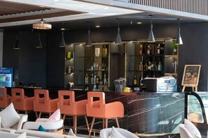 Un espace bar avec des sièges, un comptoir et des étagères remplies de bouteilles.