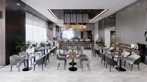 A modern dining area with multiple tables and chairs, a central bar area, and a decorative ceiling light fixture. - Wyndham Garden Legend Halong (Ha Long)