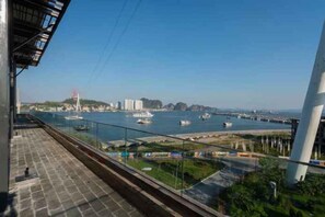 A view from a high vantage point overlooking a body of water with boats, a bridge, and buildings in the distance. - Wyndham Garden Legend Halong (Ha Long)