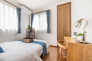 Una camera da letto con un letto, una scrivania, una sedia, una porta in legno e una finestra con tende.