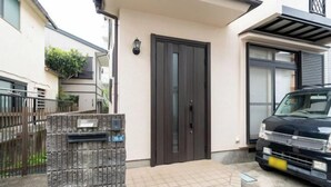 A modern house with a dark front door, a mailbox, and a parked car. - Hatagaya House (Tokyo)