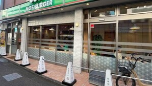 A restaurant with a green and white sign, a bicycle parked outside, and a glass door entrance.