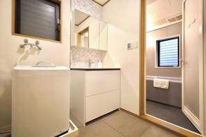 Un baño con lavabo, espejo y una toalla colgada en la pared.
